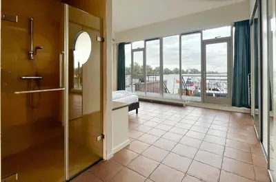 a bathroom with a glass shower and a large window at Sterrenzicht by Droomvilla in Uitgeest