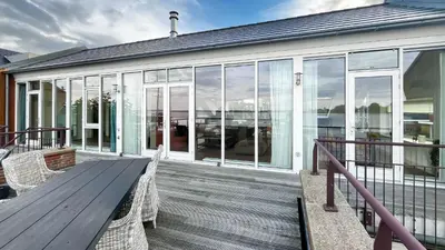 a deck with a wooden table and chairs on a house at Sterrenzicht by Droomvilla in Uitgeest