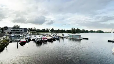 a group of boats docked at a dock on a lake at Sterrenzicht by Droomvilla in Uitgeest