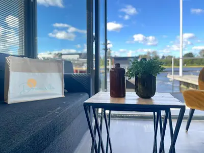 a table with a bottle and a plant on it at Golfzicht by Droomvilla in Uitgeest