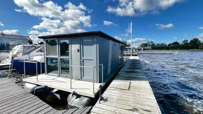 a small house on a dock on a body of water at Golfzicht by Droomvilla in Uitgeest