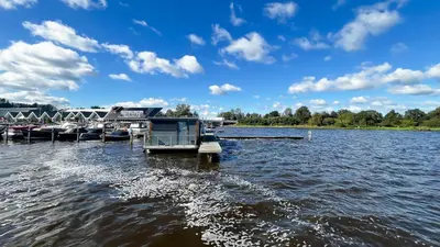 a group of boats docked at a dock on a lake at Golfzicht by Droomvilla in Uitgeest