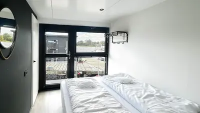 a white bed in a room with a large window at Prachtzicht by Droomvilla in Uitgeest