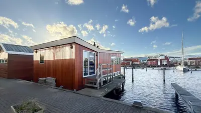 a small house on a dock on a body of water at Jachtzicht by Droomvilla in Uitgeest