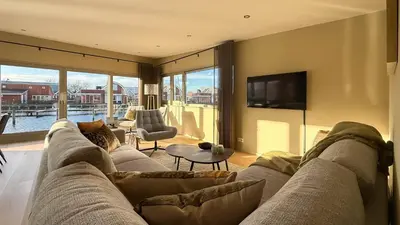 a living room with a couch and a tv at Jachtzicht by Droomvilla in Uitgeest