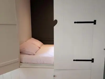 a bedroom with a bed in a room with doors at Bedstee in de polder in Egmond aan den Hoef