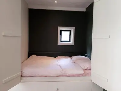 a bedroom with a bed with a black wall at Bedstee in de polder in Egmond aan den Hoef
