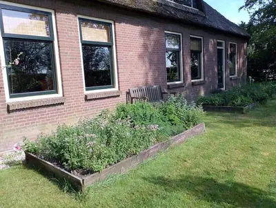 a house with a bench and some plants in the yard at Bedstee in de polder in Egmond aan den Hoef
