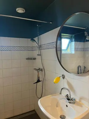a bathroom with a shower with a sink and a mirror at Bedstee in de polder in Egmond aan den Hoef