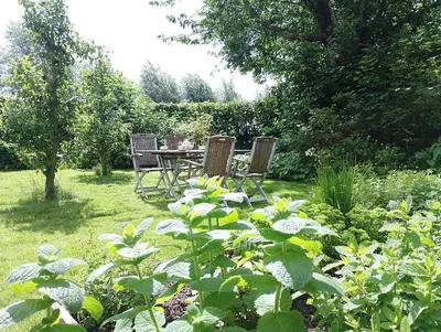 a garden with a table and chairs in the grass at Bedstee in de polder in Egmond aan den Hoef