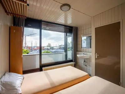 a bedroom with two beds and a window with a sink at De Kaag Watersport Groepsaccommodatie - 50 pers in Kaag