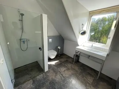 a bathroom with a shower and a sink and a toilet at Luxe vakantievilla met jacuzzi in Zeewolde