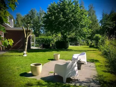 two white chairs sitting on a sidewalk in a yard at Luxe vakantievilla met jacuzzi in Zeewolde