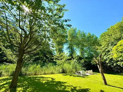a park with two chairs and trees in the grass at Luxe vakantievilla met jacuzzi in Zeewolde