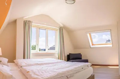 a bedroom with a bed and a chair and a window at Vakantiepark Duinrust in Noordwijk