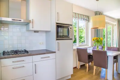 a kitchen with a white refrigerator and a table with chairs at Vakantiepark Duinrust in Noordwijk