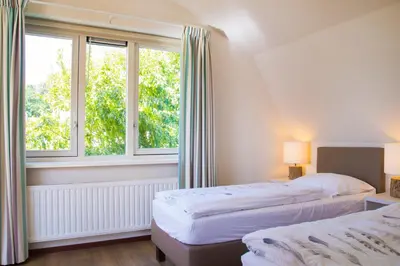 two beds in a room with two windows at Vakantiepark Duinrust in Noordwijk