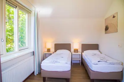two beds in a room with two windows at Vakantiepark Duinrust in Noordwijk