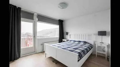 a bedroom with a bed and a large window at Nice Spacious House Near Amsterdam And Schiphol in Zwanenburg