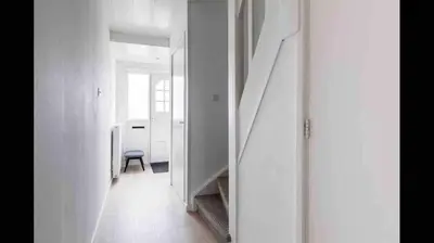 a white hallway with a chair and a stair case at Nice Spacious House Near Amsterdam And Schiphol in Zwanenburg