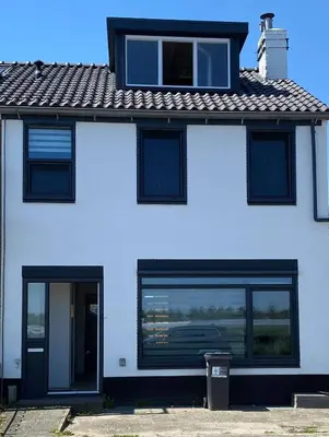 a white house with black windows and a roof at Nice Spacious House Near Amsterdam And Schiphol in Zwanenburg