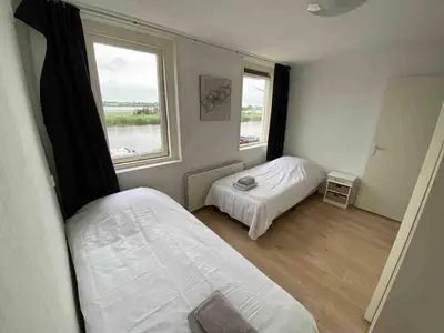 a small bedroom with two beds and a window at Nice Spacious House Near Amsterdam And Schiphol in Zwanenburg