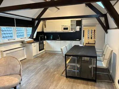 a kitchen with white cabinets and a black table and chairs at Luxury 6pers appartement Abcoude in Abcoude