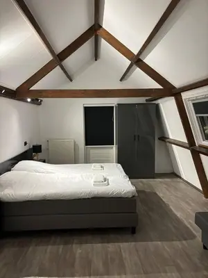a bedroom with a large bed in a room with wooden ceilings at Luxury 6pers appartement Abcoude in Abcoude