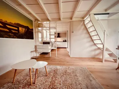 a room with a staircase and a table and chairs at Aan de dijk in Dirkshorn