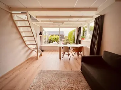 a living room with a table and a large window at Aan de dijk in Dirkshorn
