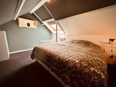 a bedroom with a bed in a room with a window at Aan de dijk in Dirkshorn