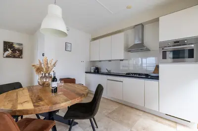 a kitchen and dining room with a wooden table at Zonlicht by Droomvilla in Egmond aan Zee