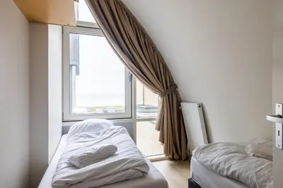 a bedroom with two beds and a large window at Zonlicht by Droomvilla in Egmond aan Zee