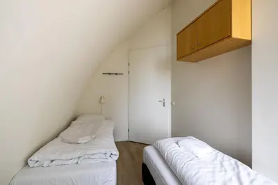 two beds in a room with white walls at Zonlicht by Droomvilla in Egmond aan Zee