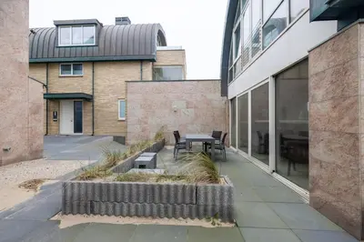 a courtyard with a table and chairs in a building at Zonlicht by Droomvilla in Egmond aan Zee