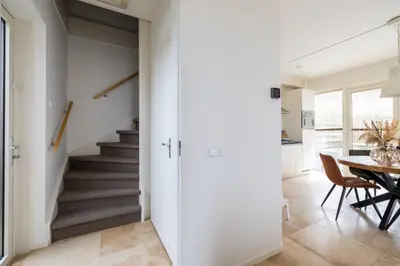 a hallway with stairs and a dining room with a table at Zonlicht by Droomvilla in Egmond aan Zee