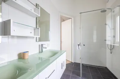 a white bathroom with a sink and a shower at Zonlicht by Droomvilla in Egmond aan Zee