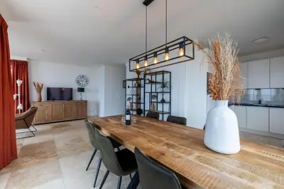 a dining room with a table with chairs and a vase at Sterrenlicht by Droomvilla in Egmond aan Zee