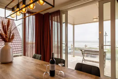 a dining room with a table with a bottle of wine at Sterrenlicht by Droomvilla in Egmond aan Zee