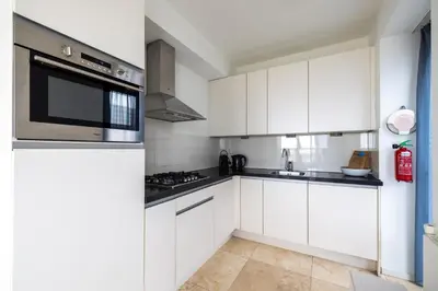 a kitchen with white cabinets and a microwave at Zilverlicht by Droomvilla in Egmond aan Zee