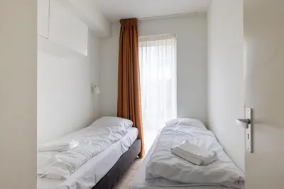two beds in a room with a window at Zilverlicht by Droomvilla in Egmond aan Zee