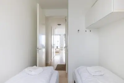two white beds in a white room with a hallway at Zilverlicht by Droomvilla in Egmond aan Zee