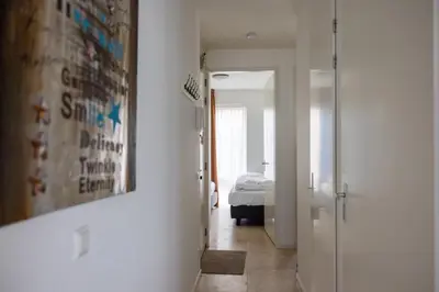 a hallway with a room with a bed and a door at Zilverlicht by Droomvilla in Egmond aan Zee