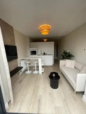 a living room with a white couch and a kitchen at Joysea Appartments in Zandvoort