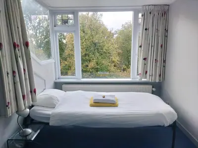 a bed in a room with a large window at Historic canal house in green residential area in Utrecht