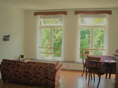 a living room with a couch and a table and windows at Historic canal house in green residential area in Utrecht