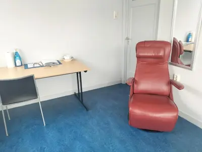 a red chair sitting in a room with a desk at Historic canal house in green residential area in Utrecht