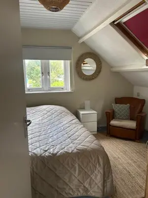 a bedroom with a bed and a chair and a window at BeJa bij strand en duin in Egmond aan Zee