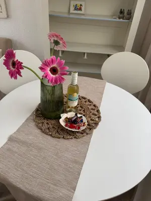 a table with a vase with flowers and a bottle on it at BeJa bij strand en duin in Egmond aan Zee