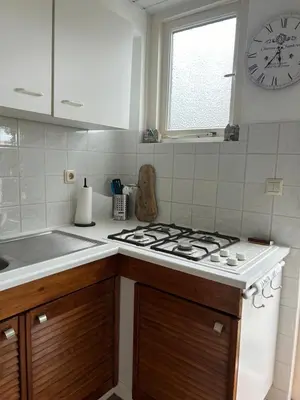 a kitchen with a stove and a clock on the wall at BeJa bij strand en duin in Egmond aan Zee